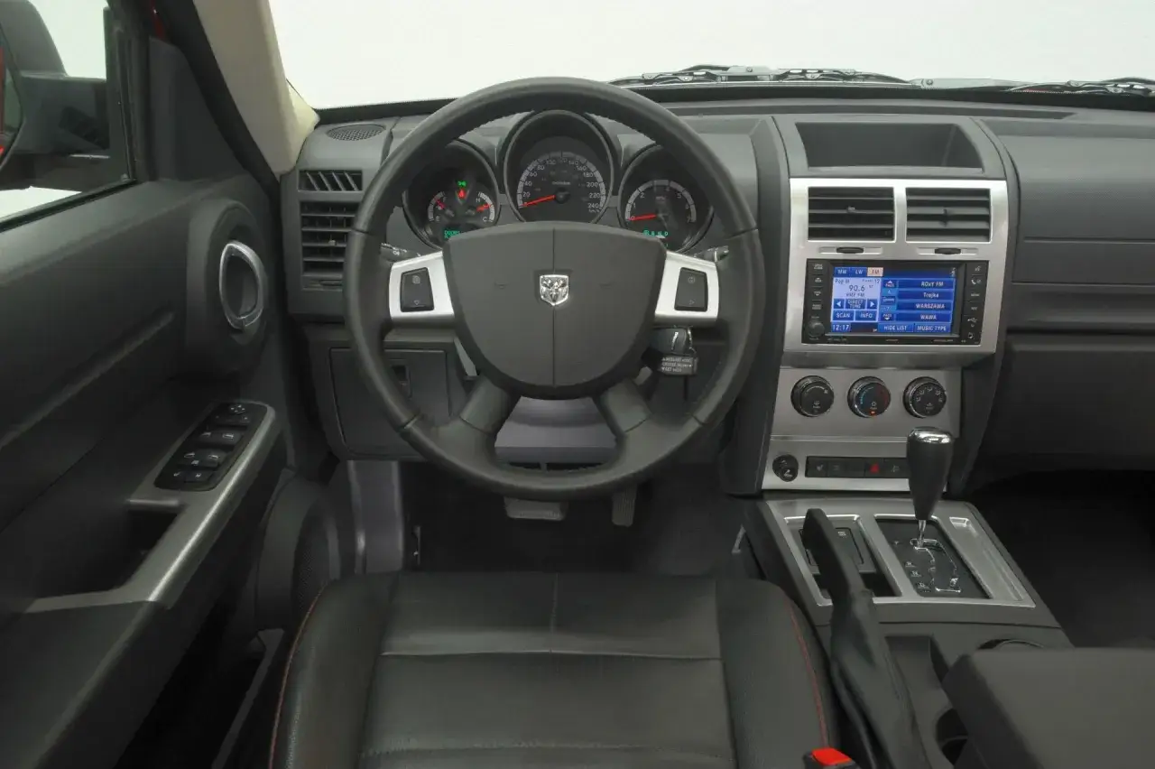 Wnętrze Dodge Nitro z czarną skórzaną tapicerką, kierownicą i panelem radia.