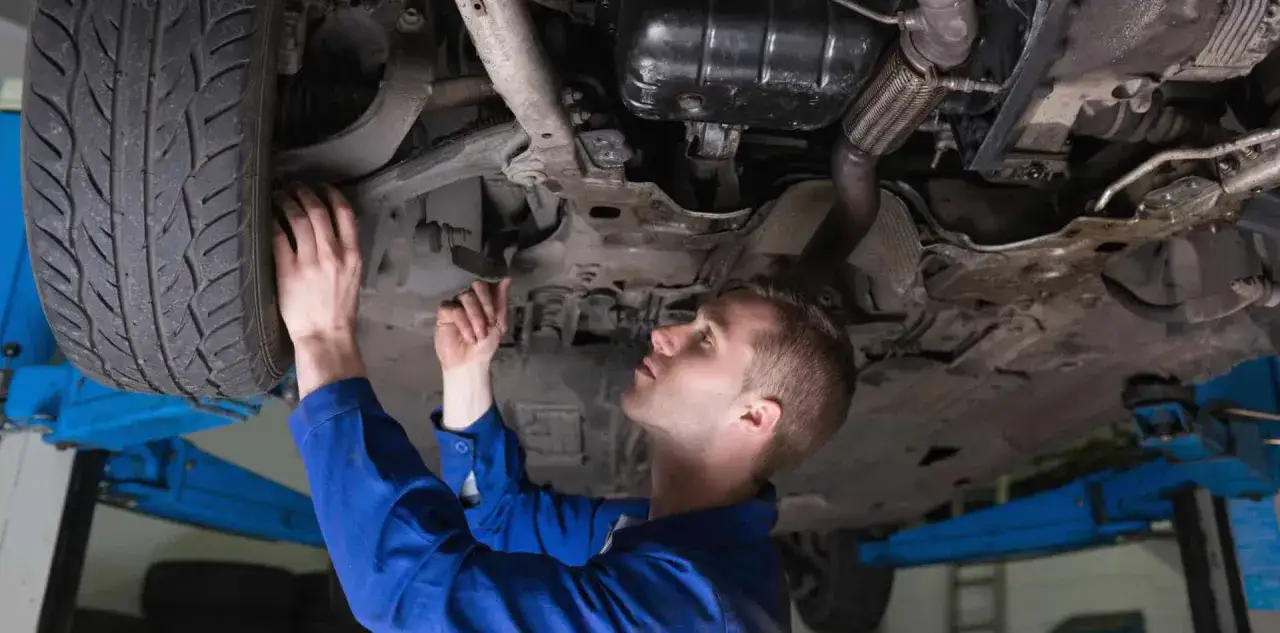 Mechanik sprawdza podwozie auta, szukając objawów zużycia łącznika stabilizatora.