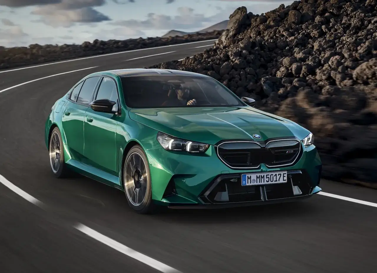 Zielony BMW M5 2025 pędzi po krętej drodze wśród wulkanicznych krajobrazów.