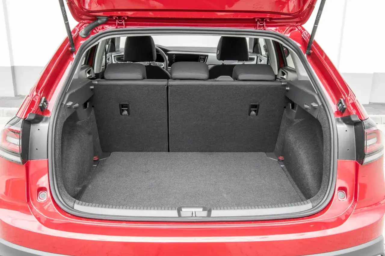 Czerwony Volkswagen Taigo z otwartym bagażnikiem. Wnętrze jest puste, gotowe na bagaże.
