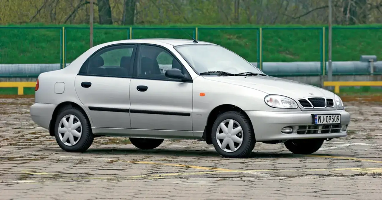 Srebrny sedan Daewoo Lanos stoi na betonowym placu.