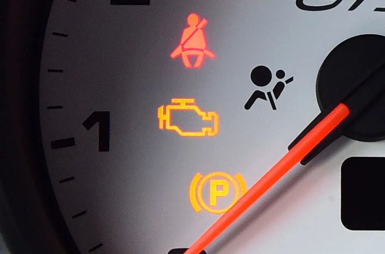 Kontrolka silnika świeci się, a Ty zastanawiasz się, jak skasować błąd check engine bez komputera? Na desce rozdzielczej widać też kontrolkę pasów i hamulca ręcznego.