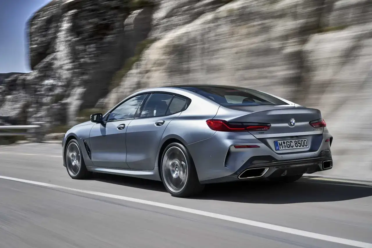 Srebrne BMW 840d pędzi po górskiej drodze, ukazując dynamiczną sylwetkę i sportowe detale.