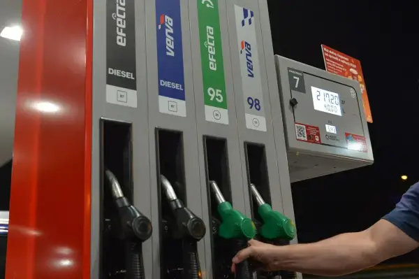 Dłoń sięga po dystrybutor z napisem DIESEL. Na stacji paliw można wybrać różne rodzaje paliwa, w tym diesel.