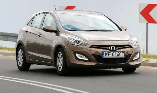 Brązowy Hyundai i30 2015 na drodze, z tablicą rejestracyjną WE 016CT.