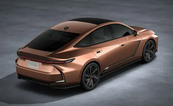 Nowy Lexus ES 500e w kolorze miedzianym, z czarnym dachem i przyciemnianymi szybami, prezentuje się elegancko na szarym tle.