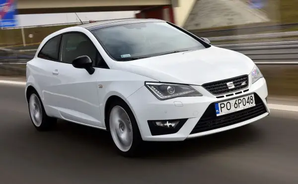 Biały Seat Ibiza 1.4 benzyna w ruchu, z czarnym dachem, na drodze.