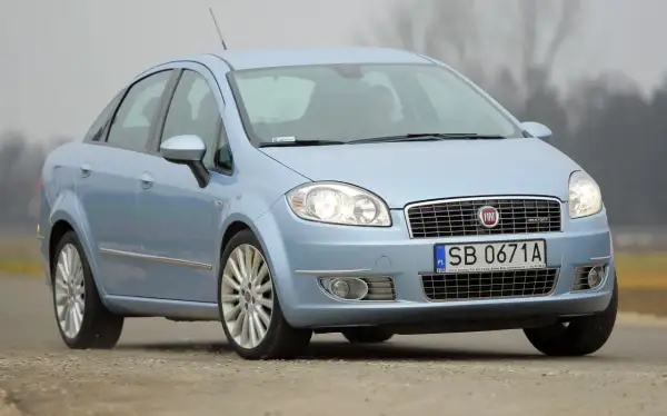 Jasnoniebieski Fiat Linea z polskimi tablicami SB 0671A jedzie po drodze.