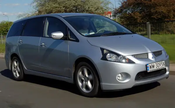 Srebrny Mitsubishi Grandis jedzie po drodze. Kierowca w jasnej koszulce prowadzi auto.