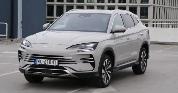 Nowy BYD Song Plus, elegancka hybryda SUV, prezentuje się na parkingu przed nowoczesnym budynkiem.