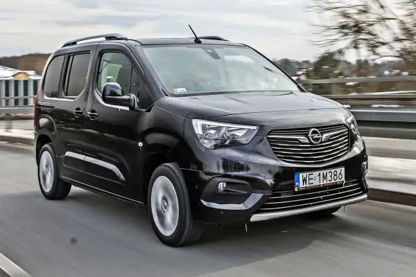 Czarny Opel Combo Life pędzi po drodze, gotowy na rodzinne przygody.