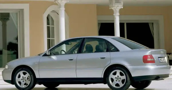 Srebrne Audi A4 B5, sedan, stoi przed budynkiem z kolumnami.