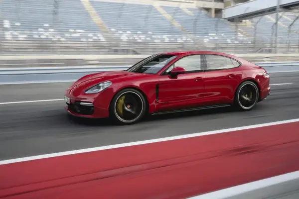 Czerwone Porsche Panamera GTS pędzi po torze wyścigowym, za nim widać trybuny.