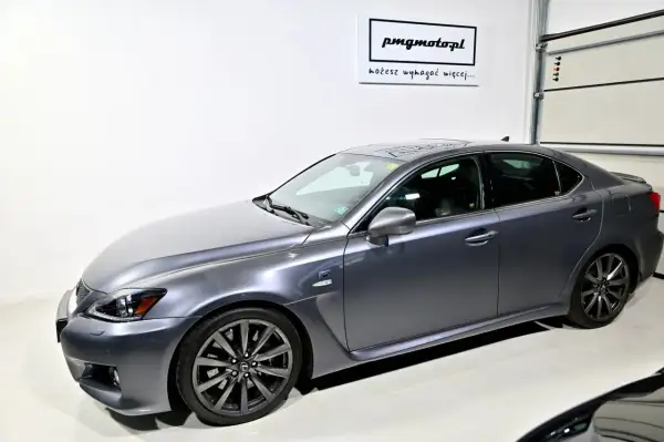 Szary Lexus IS F w garażu, z logo "pmgmotopl" na ścianie.