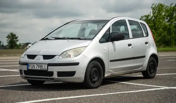 Srebrny Mitsubishi Colt z tablicą rejestracyjną PGN 798LL stoi na parkingu.