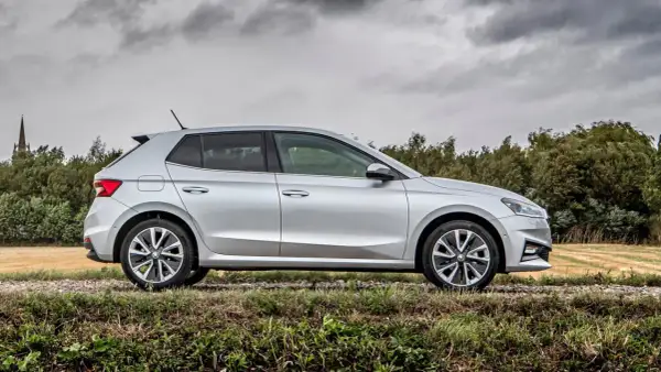 Srebrna Skoda Fabia na tle drzew i pola. Sprawdź atrakcyjne ceny używanych modeli!