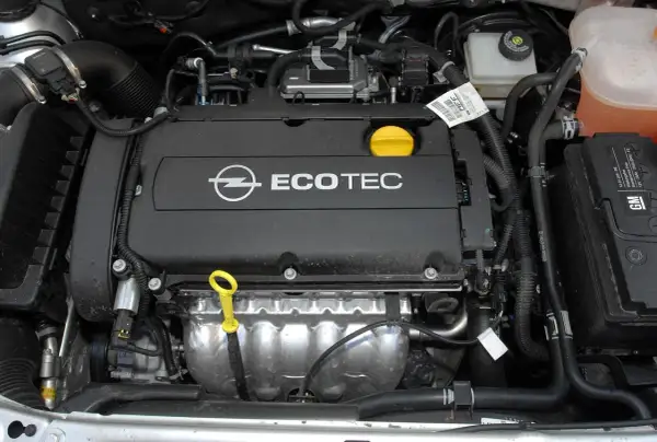 Silnik Ecotec w Oplu Astra H 1.6 benzyna. Widoczny jest blok silnika, przewody i akumulator GM.