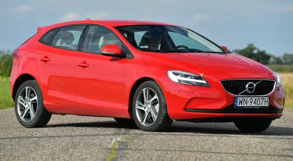 Czerwone Volvo V40 D2 na drodze, z widocznym kierowcą w okularach przeciwsłonecznych.
