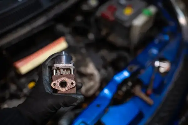 Zardzewiały zawór EGR w dłoni mechanika. Zastanawiasz się egr co to? To kluczowy element układu recyrkulacji spalin.