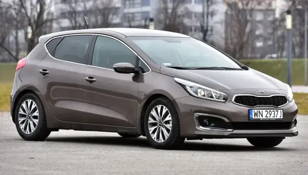 Brązowy Kia Ceed 1.6 benzyna z polskimi tablicami rejestracyjnymi WN 2937J zaparkowany na zewnątrz.