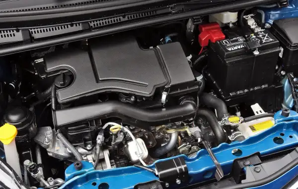 Silnik Toyoty Yaris 2017: czarny plastikowy osłona, akumulator Varta, niebieska belka.