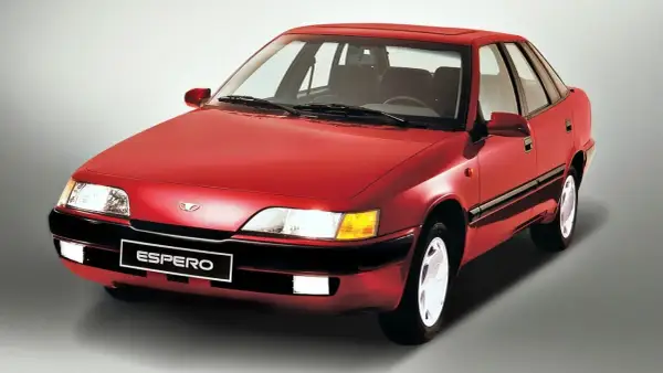 Czerwony Daewoo Espero z lat 90. na szarym tle. Klasyk z przeszłości, który wciąż budzi nostalgię.