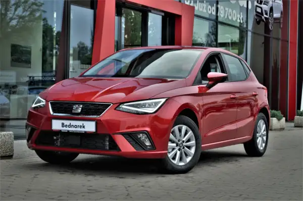 Czerwony SEAT Ibiza, jeden z popularnych modele, zaparkowany przed salonem samochodowym.