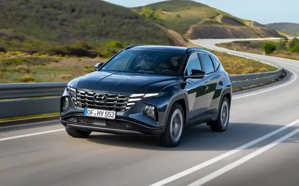Ciemnoszary Hyundai Tucson na zakręcie drogi. Sprawdź jego imponujące hyundai tucson wymiary i ciesz się jazdą po malowniczej trasie.