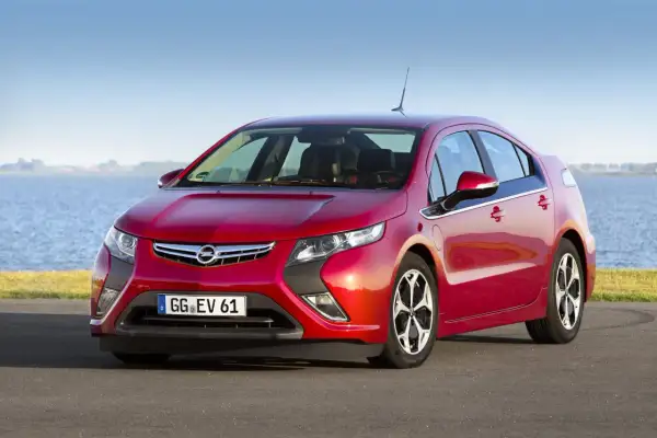 Czerwony Opel Ampera stoi nad jeziorem, gotowy na ekologiczną podróż.
