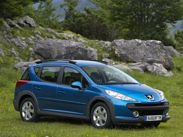 Niebieski Peugeot 207 SW na tle skalistego, zielonego krajobrazu. Idealny na wycieczkę poza miasto.