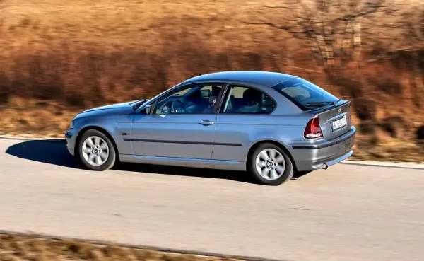 Srebrne BMW Compact w ruchu, z rozmytym tłem.